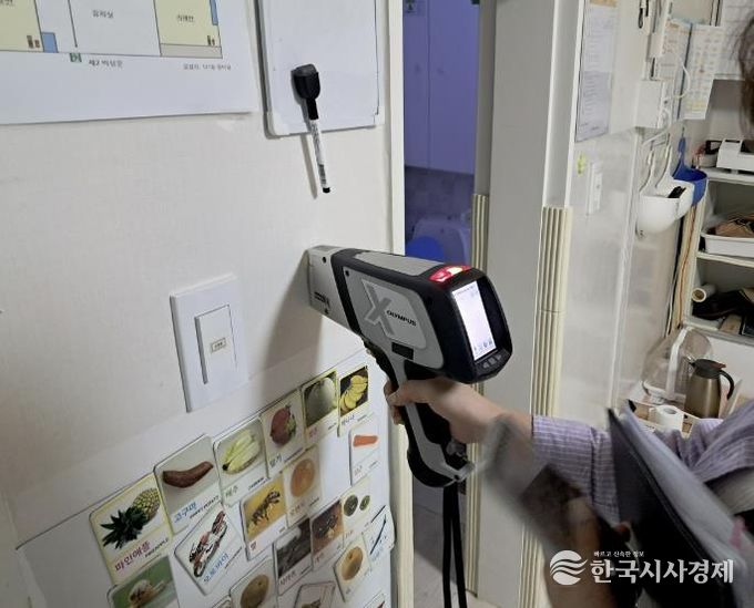 구청 관계자가 어린이집 실내 벽에 사용된 도료의 중금속 함량을 측정하고 있다