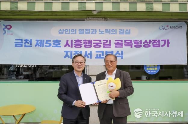 유성훈 금천구청장(왼쪽)과 김명식 상인회장이 골목형상점가 지정서 교부식을 진행하고 기념촬영을 하고 있다