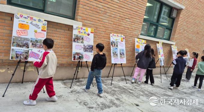 덕신초 학생들이 교내에 전시된 '우리들의 행복한 순간' 사진을 관람하고 있다.