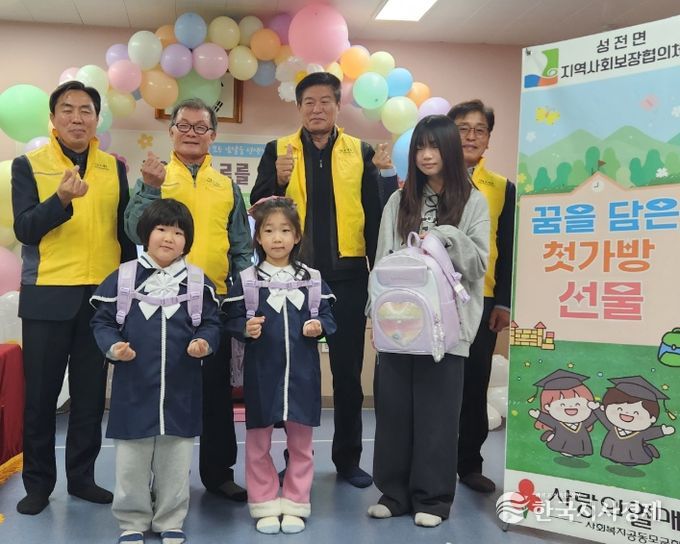 성전면 병설유치원 졸업식에서 성전면지사협 위원들이 예비 초등학생들에게 책가방을 전달 하고 있다.