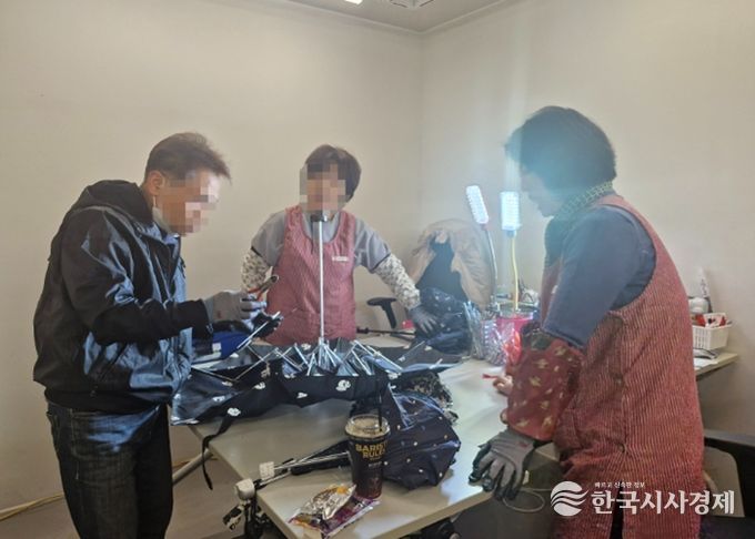 우산수리센터에서 고장난 우산을 수리하고 있고 있다.