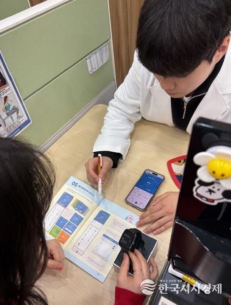 모바일 헬스케어사업 참여자가 모바일 앱(채움건강)과 활동량계(스마트밴드)에 대한 설명을 듣고 있다.