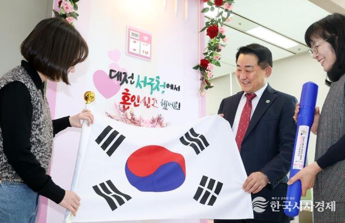 서철모 서구청장이 구청 민원실을 방문한 국제결혼 부부에게 태극기를 전하고 있다