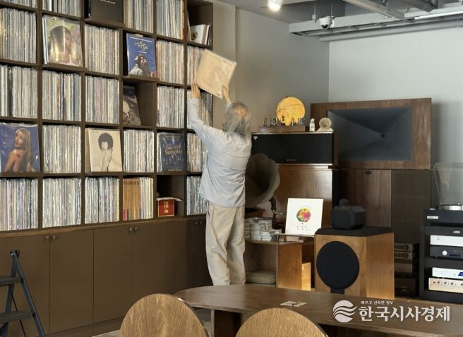 음악감상실 온 주인장이 신청곡 LP를 찾고 있다.